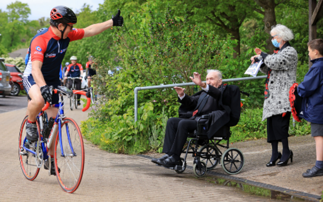 A cyclist gives Johnny Johnson a thumbs up as he passes by