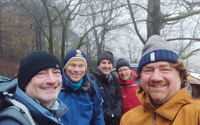 April Fools Club members in jackets and hats smiling in front of winter trees