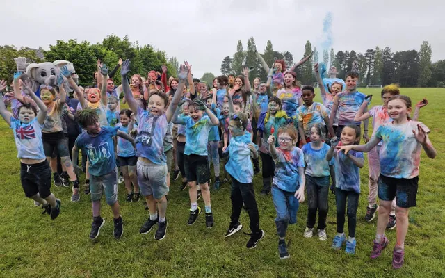 Group of young people cheering covered in colours