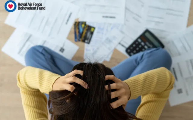 Woman holding head stressed with bills around her