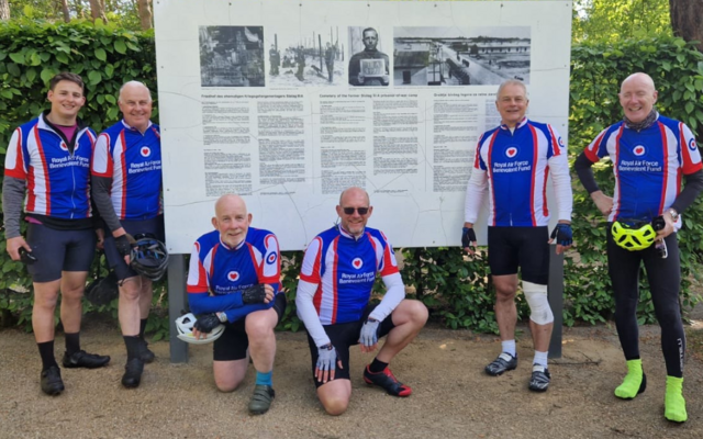 Cyclists in their Fund jerseys standing in front of museum board