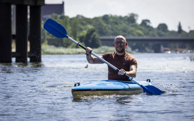 John in blue kayak on river with blue oars