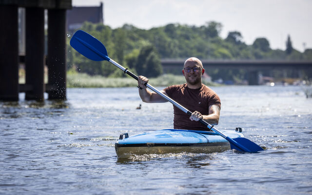 John in blue kayak on river with blue oars