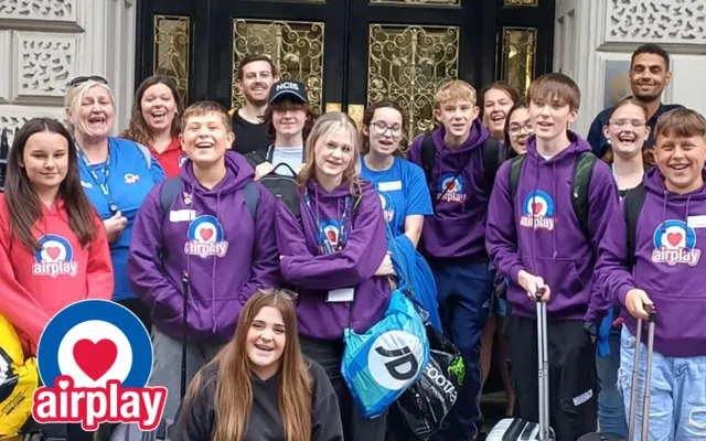 Group of young people in purple and blue Airplay hoodies standing in group posing