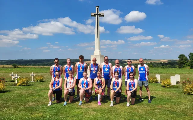 Group of runners posing standing and knelt in front of memorial