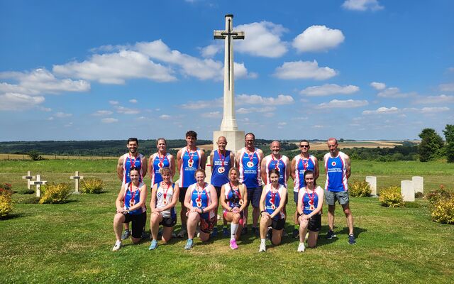 Group of runners posing standing and knelt in front of memorial