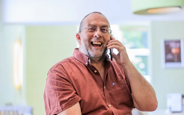 An RAF veteran on the phone, smiling and looking very happy
