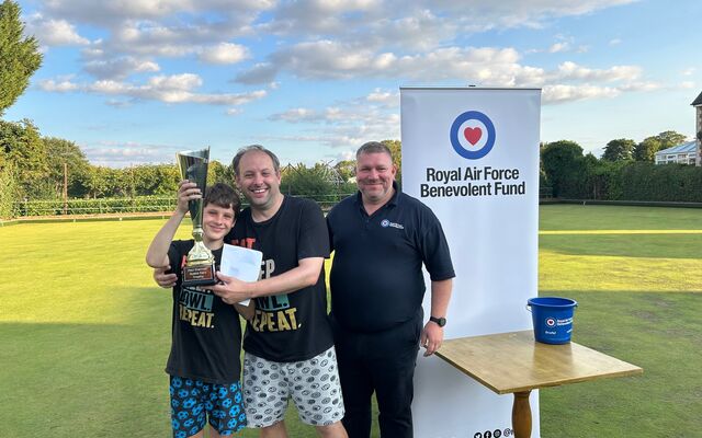 2 people holding winners trophy, Fund member of staff on field