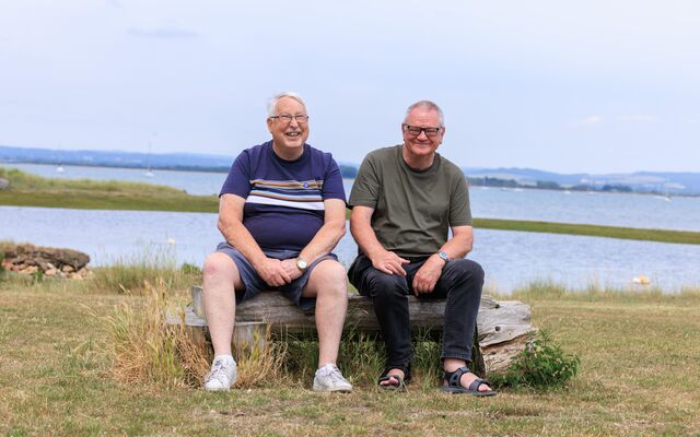 Two gentleman sitting together in front of lake on break