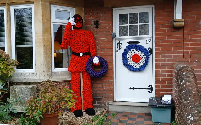 Airman made out of poppies outside house with RAF wreath on door