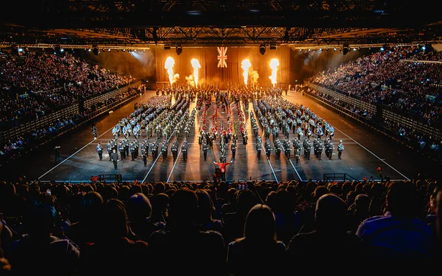 Image of military parade with fire pyrotechnics in background