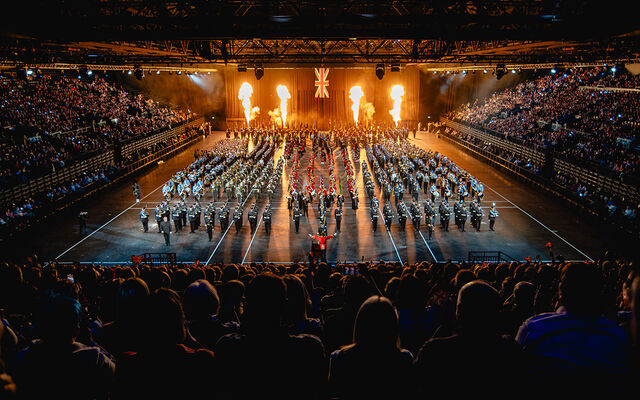 Image of military parade with fire pyrotechnics in background