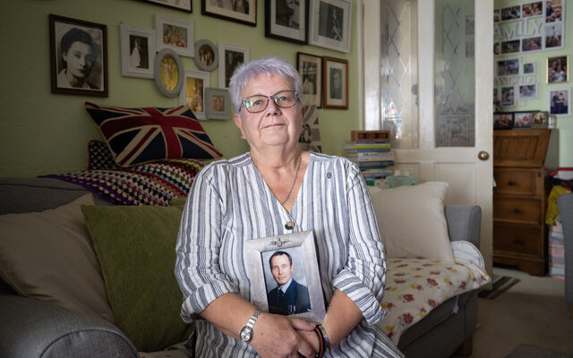 Caroline sat on her sofa holding photo of her husband