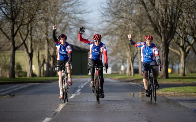 3 cyclists on their bikes with 1 arm raised 