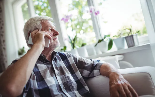 Man in 60s on phone looking out of window