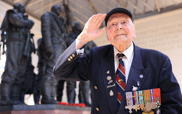 WW2 veteran George Dunn salutes in front of the Bomber Command Memorial statue