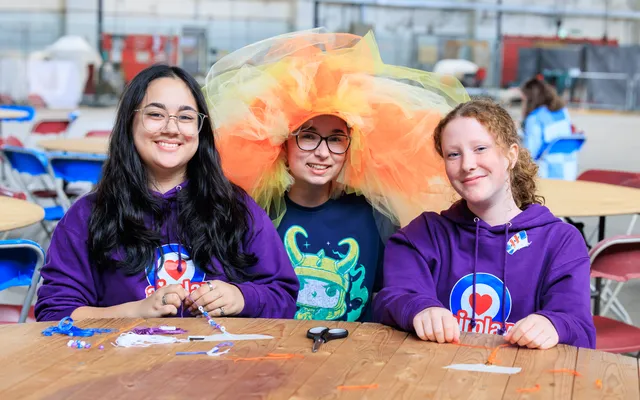 three Airplay attendees sat at craft table one with elaborate head dress on
