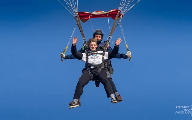 Kai holding onto parachute mid-air