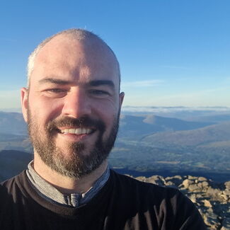 Image of an RAF veteran on a walk with a view of mountains behind him