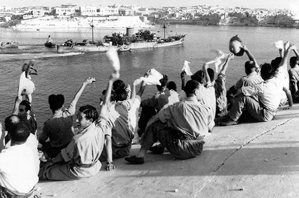 Arrival of the first ships in Malta: The SS Rochester Castle passes a group of military personnel and civilians as she enters Grand Harbour, Malta in the afternoon of 13 August 1942.(UK Crown Copyright / MOD. Courtesy of Air Historical Branch, RAF)