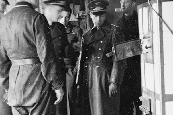 A group of German officers look at the entrance to a tunnel dug in a hut by Prisoners of War at Stalag Luft III.