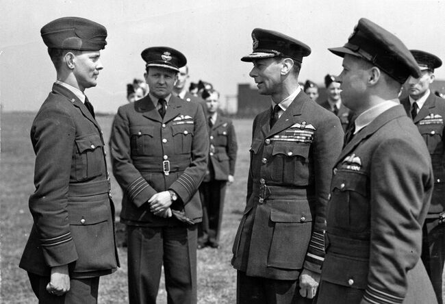 King George VI, accompanied by Wing Commander Guy Gibson (right) talking to Pilot Officer GL Knight RAAF, during his visit to 617 Squadron at Scampton on 27 May 1943. Knight and his crew launched the 'Upkeep' weapon which successfully breached the Eder Dam. Crown Copyright, MOD.