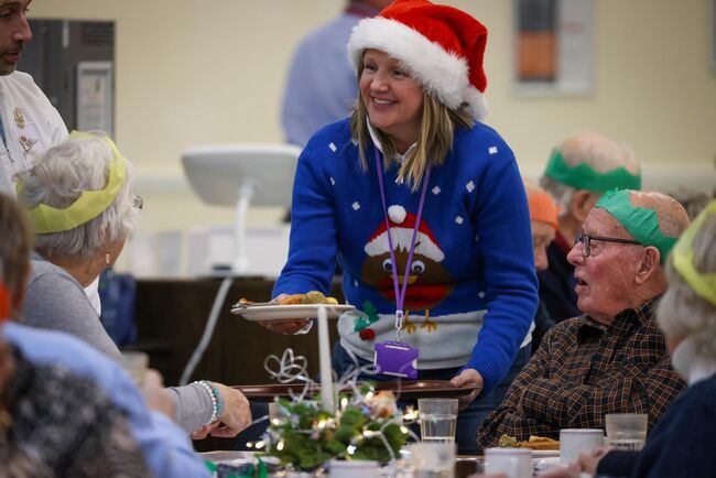 Serving personnel in santa hat with veterans smiling