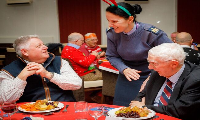Veterans at dinner table speaking to Brize Norton personnel serving