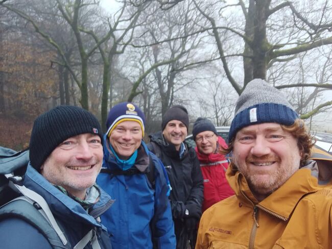 April Fools Club members in jackets and hats smiling in front of winter trees