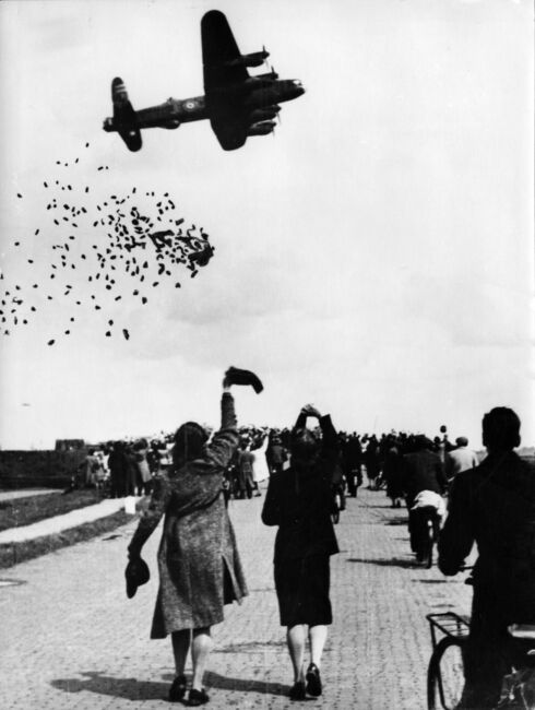 A Lancaster of Bomber Command drops food and supplies to a crowd of watching Dutch people during Operation MANNA in 1945.