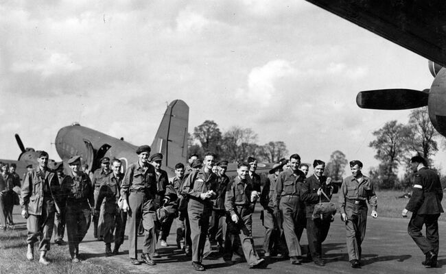 A group of prioners of war who have just returned to Britain walk away from the Dakota aircraft which had flown them to Westcott in Buckinghamshire on 15 April 1945.