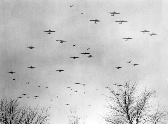 Operation VARSITY. Douglas Dakotas of 46 Group fly in formation over Wavre, Belgium, heading for the dropping zones east of the River Rhine on 24 March 1945. Above them, Dakotas towing Airspeed Horsas fly a divergent course towards their objectives.