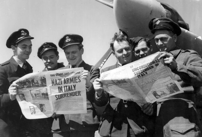 British and Dominion airmen read of the end of the Italian campaign. Reading the news in 'The Stars and Stripes' and 'Union Jack', 3 May 1945.  From left to right: Flight Lieutenant J Thompson of Glossop, Derbyshire, Flying Officer D Hunnam of Warrington, Lancashire, Flying Officer HH McHardy of Hawks Bay, New Zealand, Flying Officer R Johnston from Sydney, Australia, Flight Lieutenant J Ester, a Belgian, and Corporal WJ Cowell from Laindon, Essex.