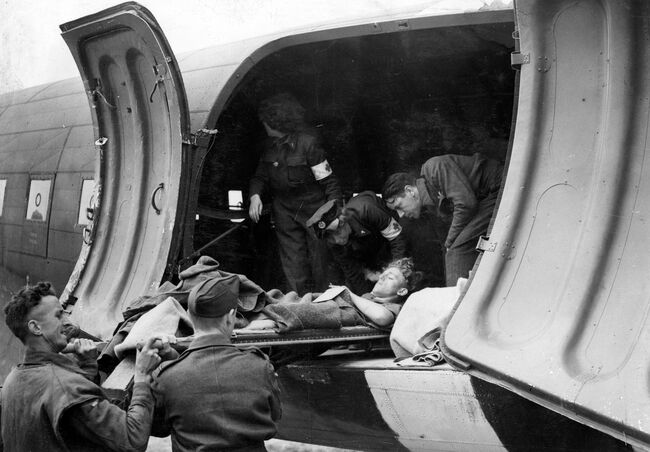 Aircrew and WAAF nursing orderlies help to load a battle casualty on a stretcher into a Douglas Dakota III of 233 Squadron at B2/Bazenville, Normandy. The RAF's first 'casevac' flights to France were mounted by Dakotas of 46 Group on 13 June 1944, and the WAAF nursing orderlies pictured were the first women to be employed on these duties.