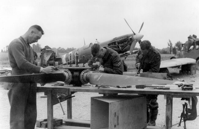 Airmen working at an RAF Salvage and Repair Unit in Normandy, 20 June 1944. Left to right: Leading Aircraftman LE Mireau from Saskatoon in Canada, Corporal KR Rowberry from Birmingham and Leading Aircraftman LB Steele from Glasgow.