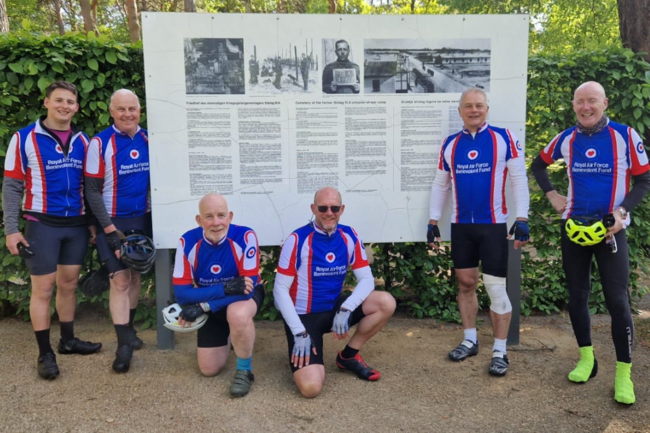 Cyclists in their Fund jerseys standing in front of museum board
