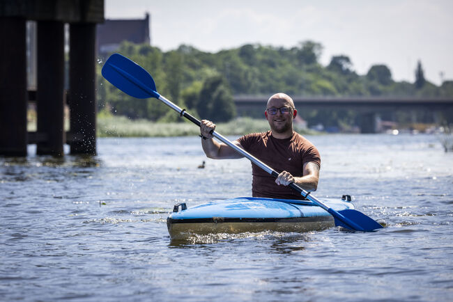 John in blue kayak on river with blue oars