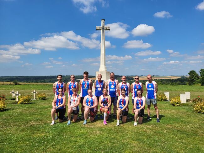 Group of runners posing standing and knelt in front of memorial