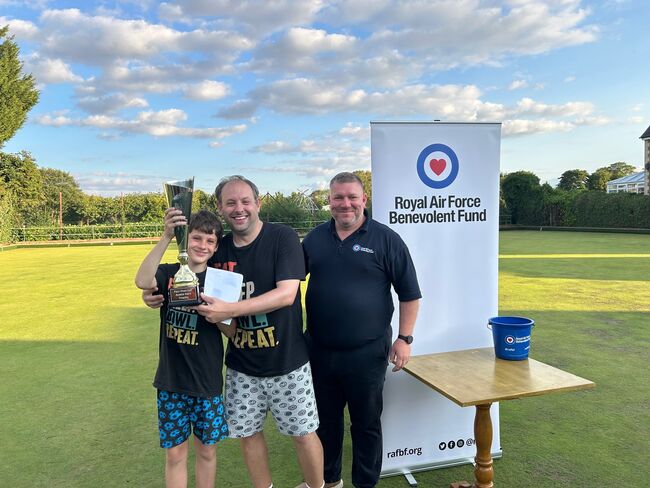 2 people holding winners trophy, Fund member of staff on field
