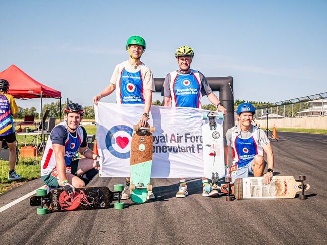 4 personnel wearing Fund vests posing at finish line with Fund flag