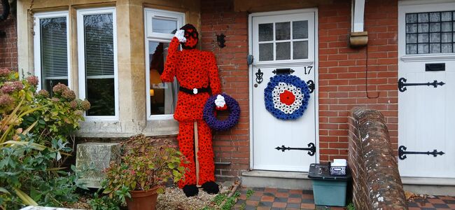 Airman made out of poppies outside house with RAF wreath on door