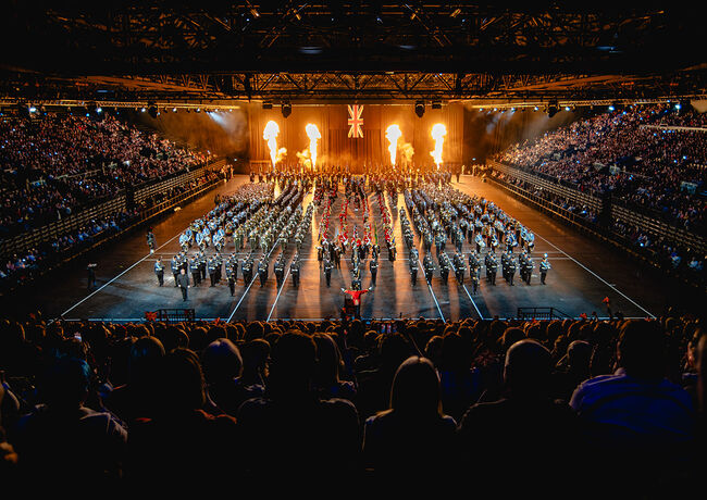 Image of military parade with fire pyrotechnics in background