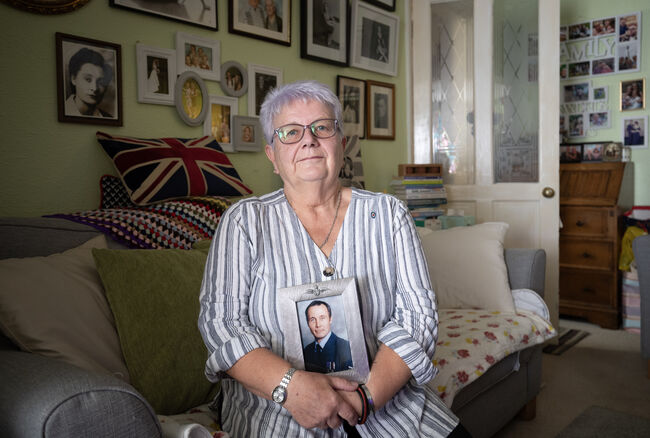 Caroline sat on her sofa holding photo of her husband