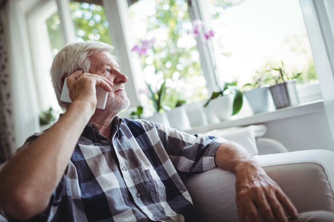 Man in 60s on phone looking out of window