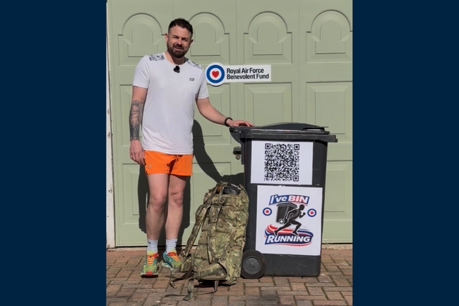 Jaime standing with camo backpack and wheelie bin