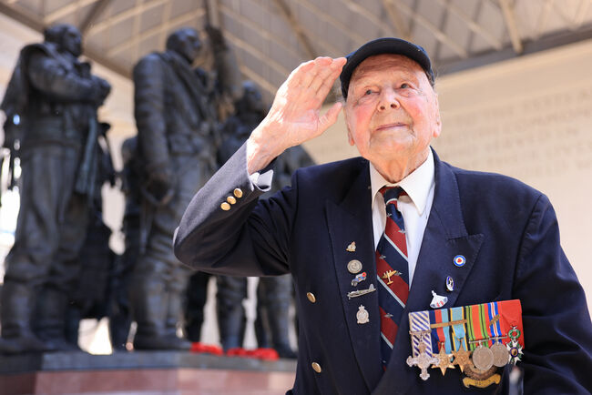 WW2 veteran George Dunn salutes in front of the Bomber Command Memorial statue