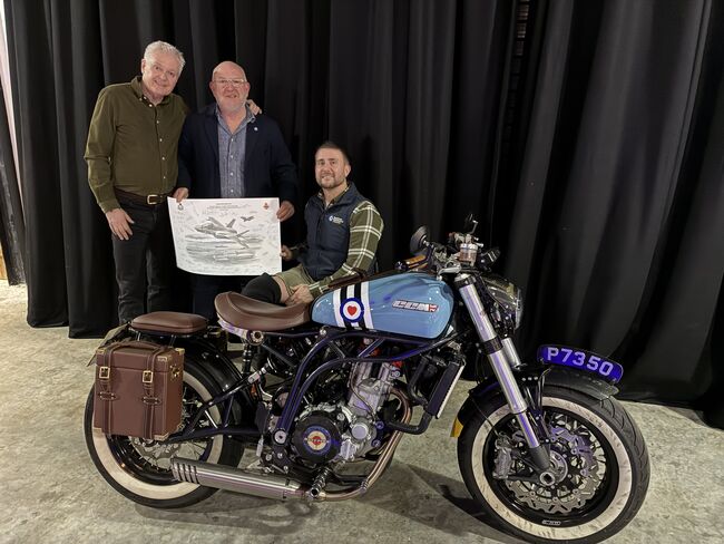 3 men including Stu holding the print in front of motorbike