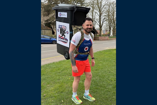 Jaime in Fund vest orange shorts and wheelie bin on back