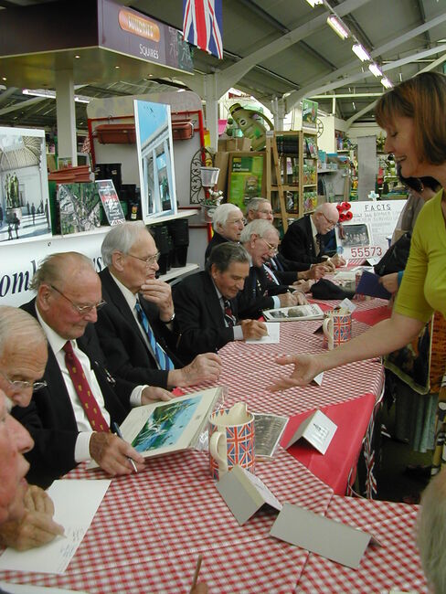 BC veterans at table signing photos