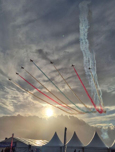 An image of the Red Arrows flypast with a setting sun in the background.